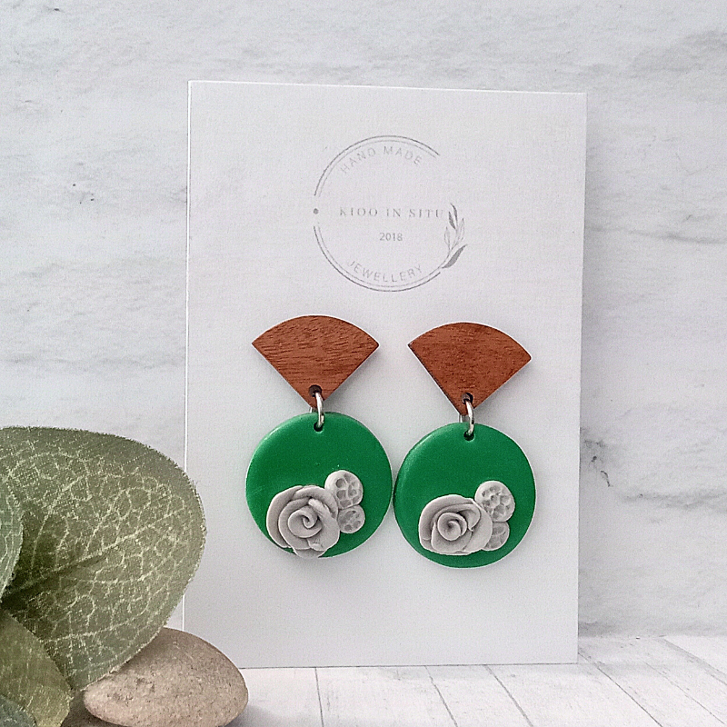 These delicate handcrafted earrings boast a captivating emerald green polymer clay with subtle grey little roses