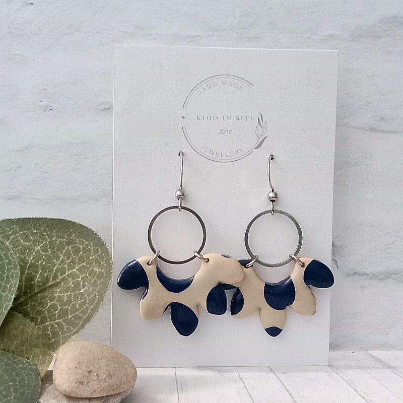 These handmade earrings feature a unique shape crafted from polymer clay in a beautiful blue and off-white pattern.